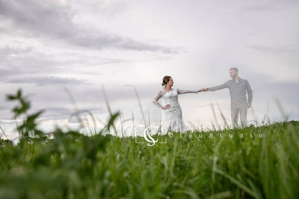 Evan Winner and Olivia Kunkler holding hands in a field. 