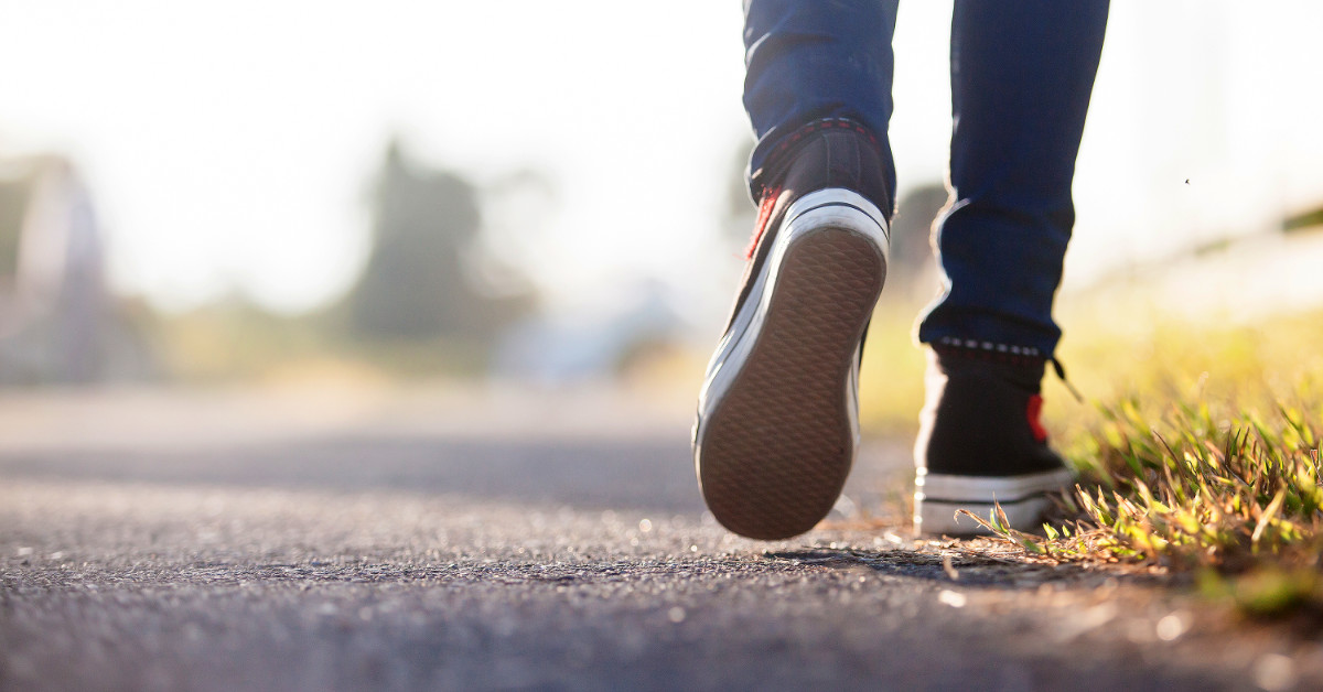 close up of someone walking on a paved path. Only the bottom portion of the legs are revealed.