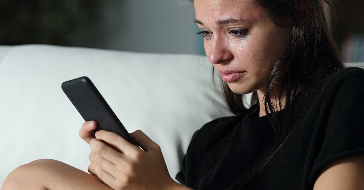 woman looking at phone while crying