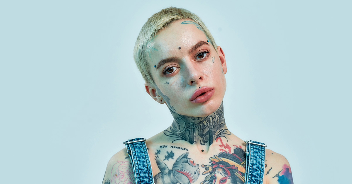 person with short blond hair and face tattoos
