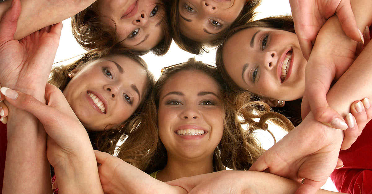 young females in a circular huddle with their heads touching