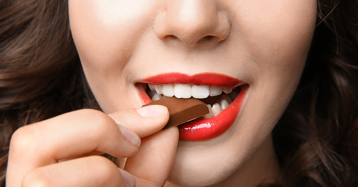 woman with red lipstick eating chocolate