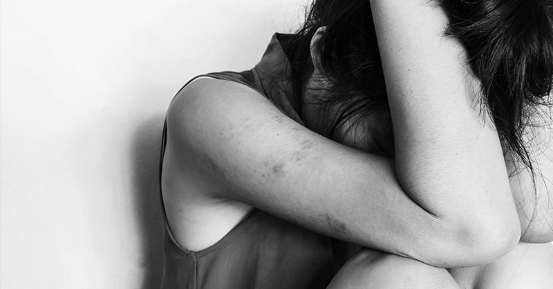 black and white image of person covering their head and face in despair