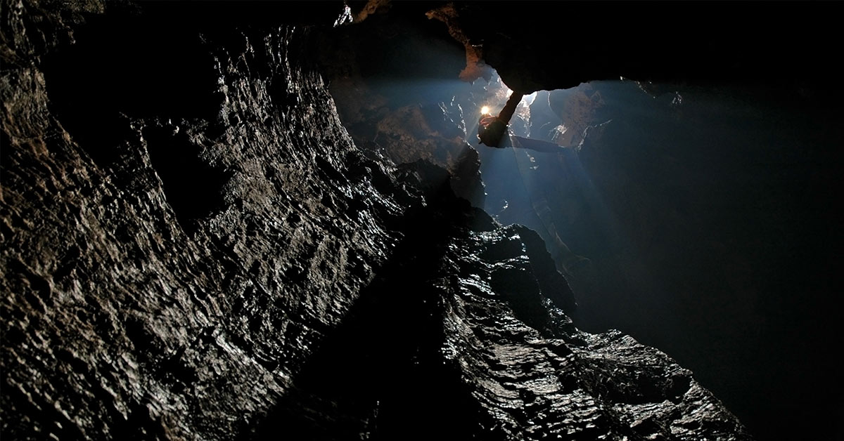 caver descending into well of hell