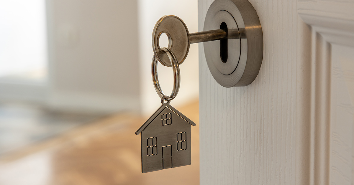 key inserted in key hole with a home shaped keychain attached