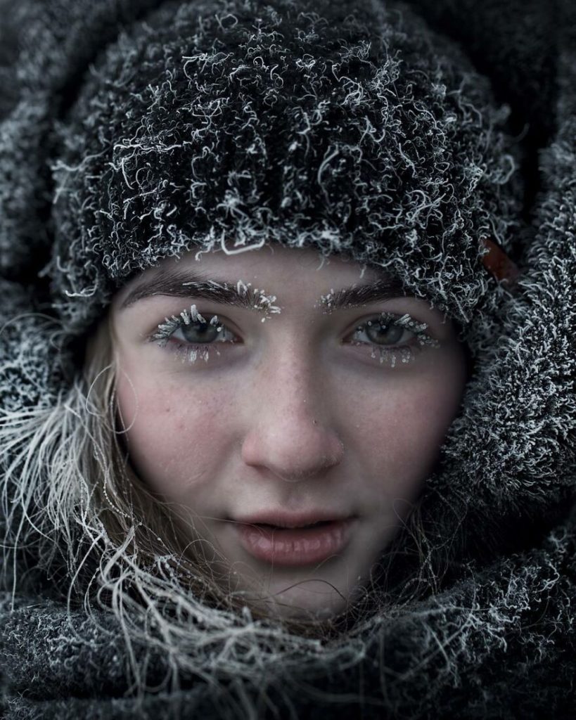 Close up a woman's face. Eye brows and lashes are frosted with snow. Photo by Aleksey Vasiliev