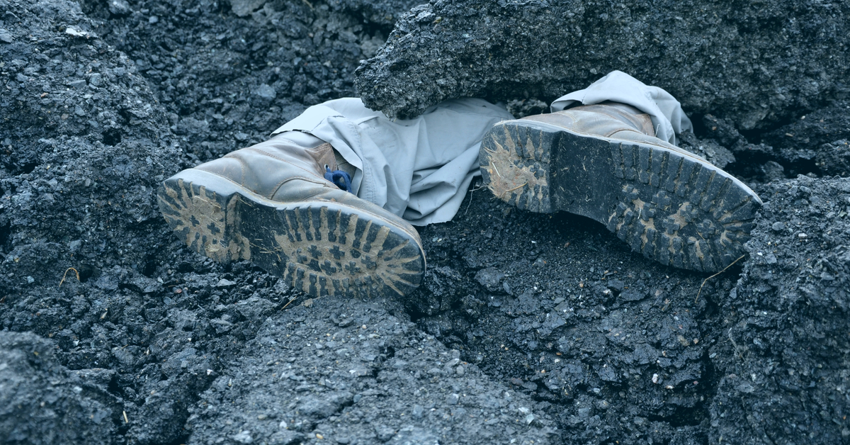 pair of mens legs sticking out from under rubble