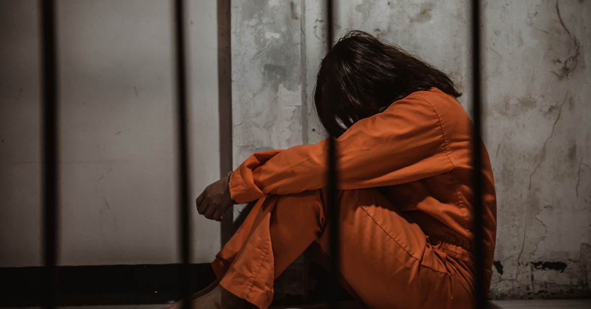 woman in jail cell wearing orange jumpsuit