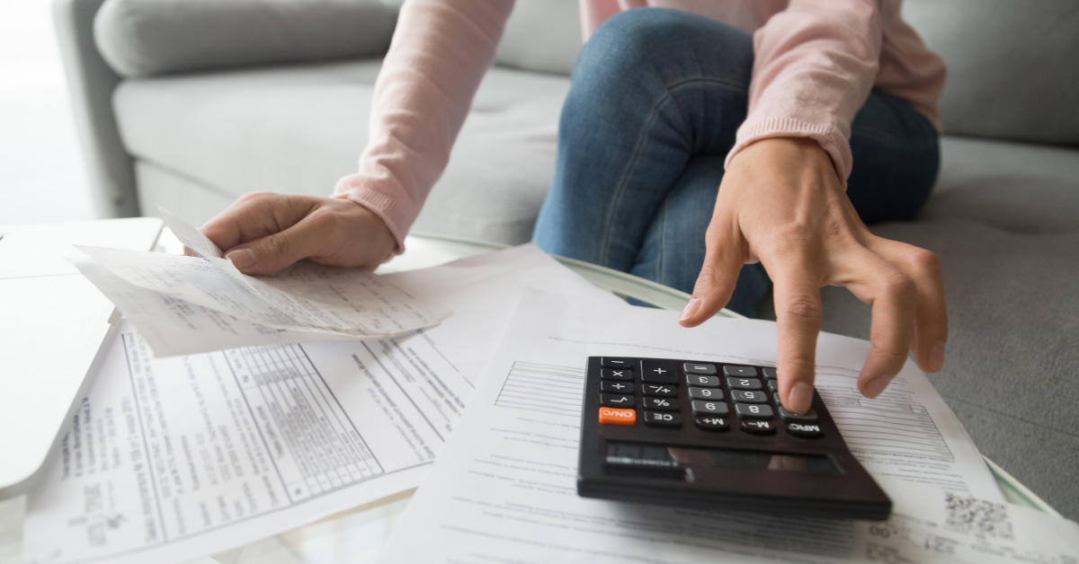 person looking at various financial papers while using calculator