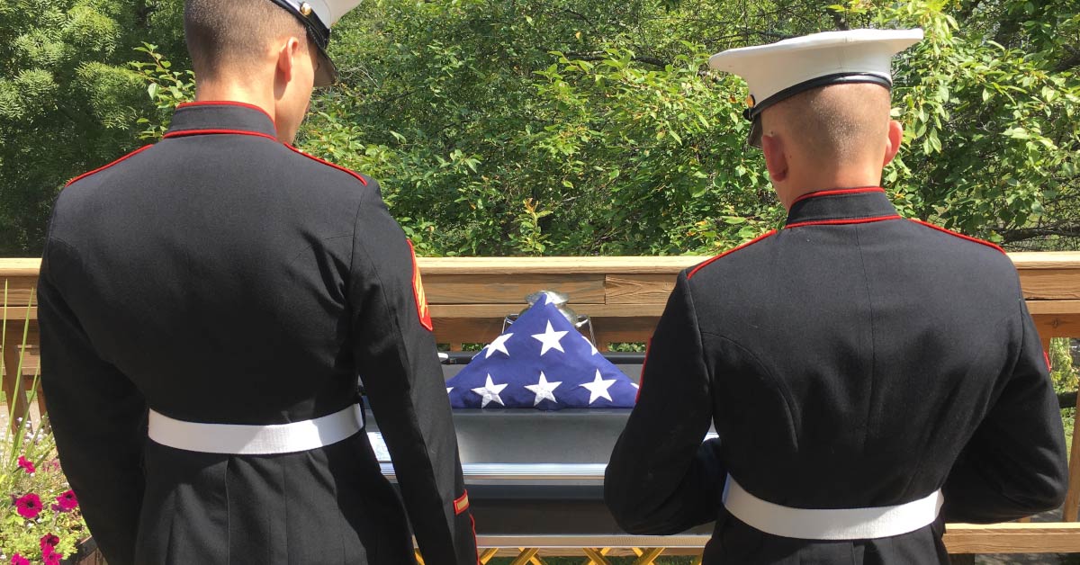 two marines standing in front of a casket paying tribute to fallen soldier