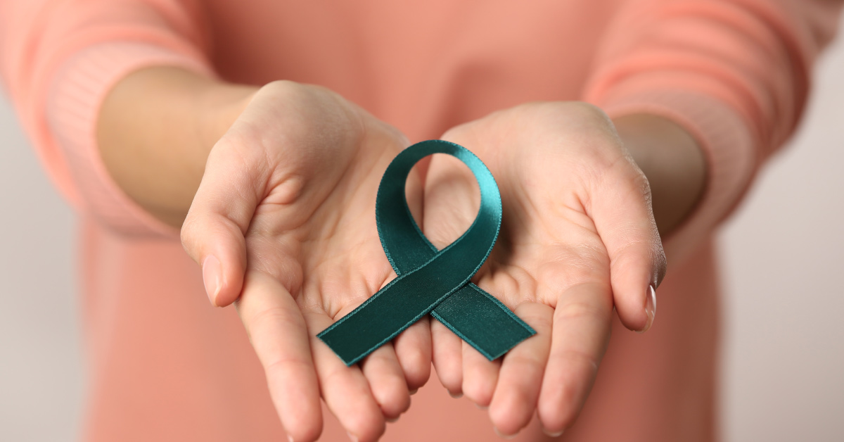 woman's hands open holding a green ribbon representing cervical cancer awareness