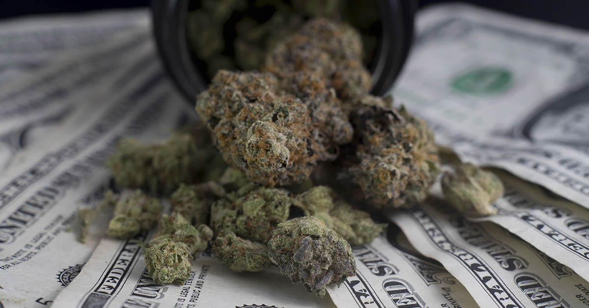 Cannabis spilled out of a jar over top of american currency