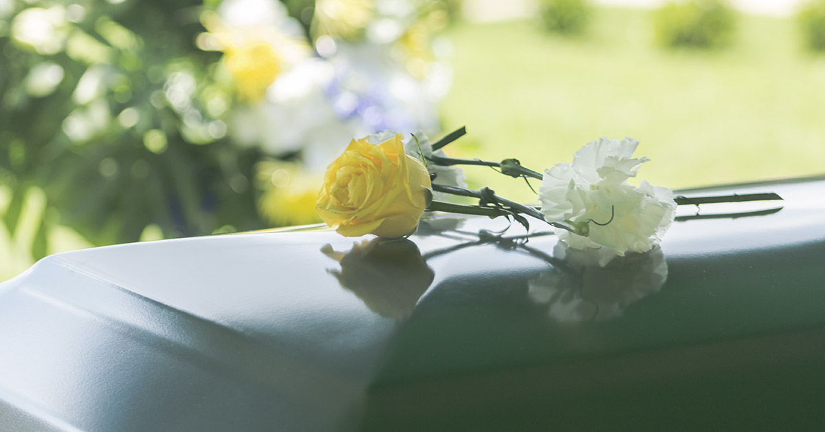 casket with a single yellow and white flower on top