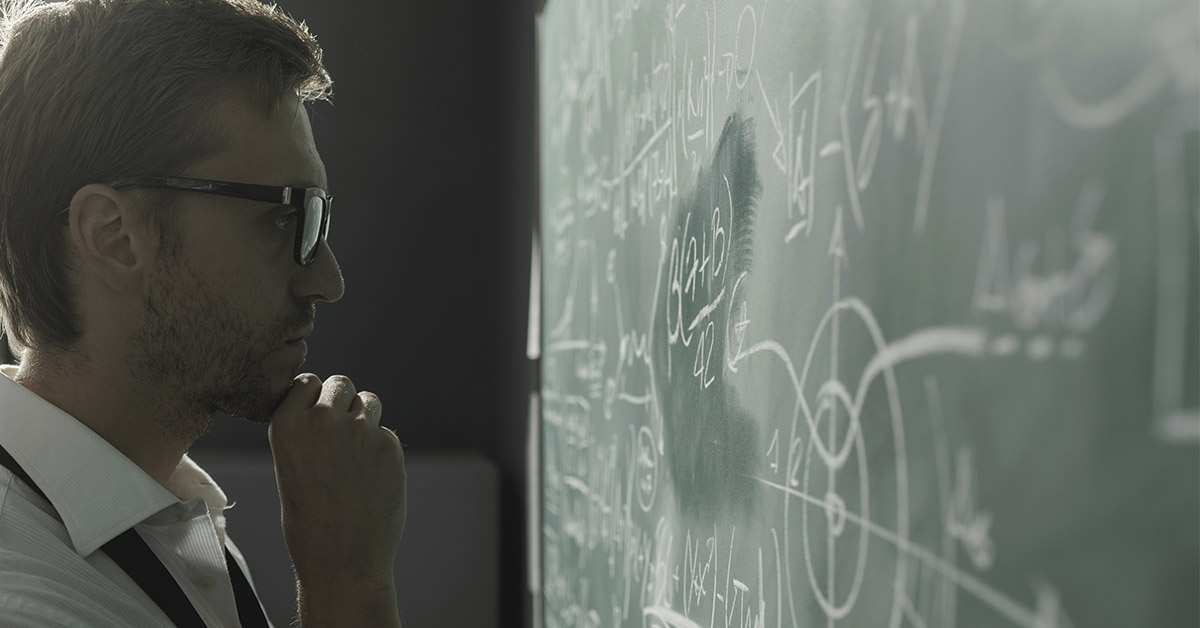 scientist pondering while looking at chalkboard filled with scientific jargon