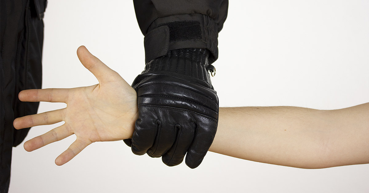 black gloved hand grabbing someone's arm