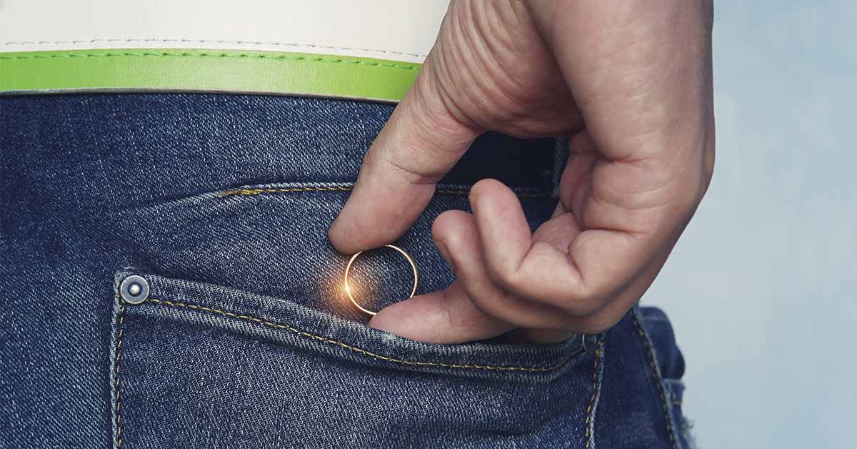 person placing wedding ring in back pocket