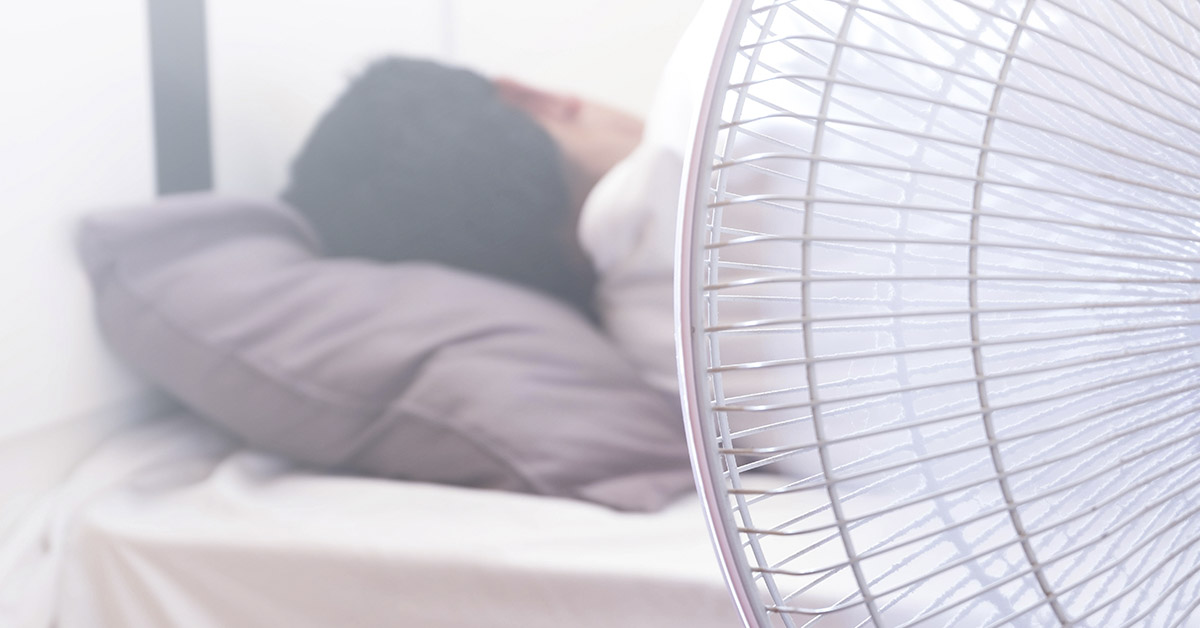 fan with person sleeping in background