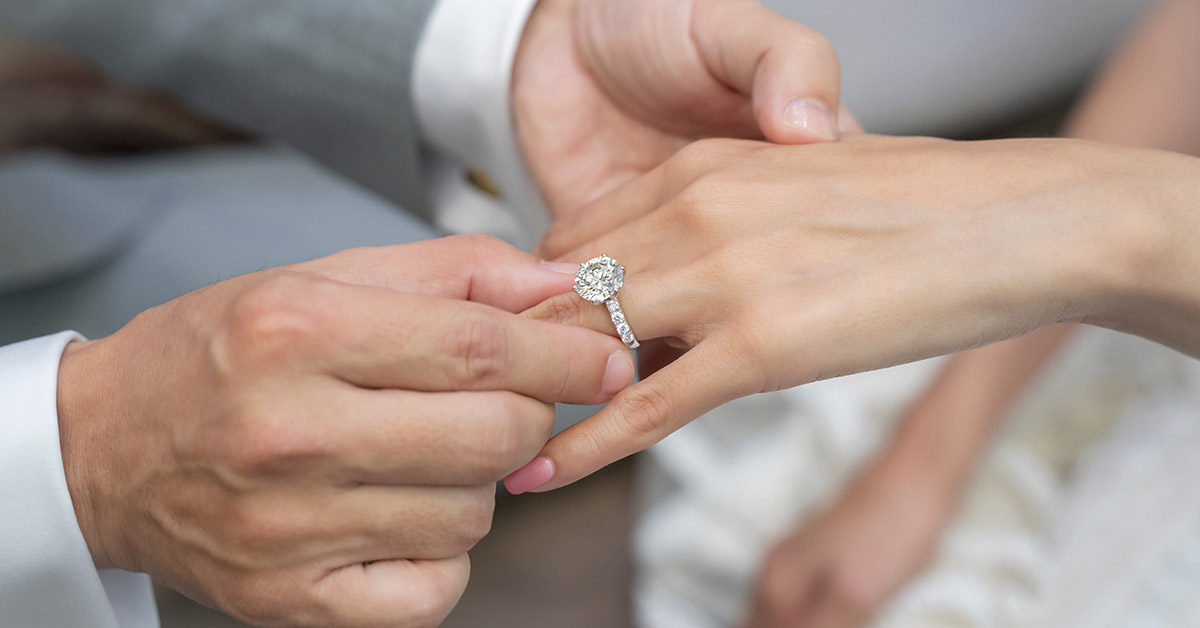 wedding ring being placed on bride's finger by groom grrom