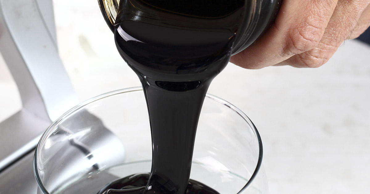 blackstrap molasses being poured into a glass bowl