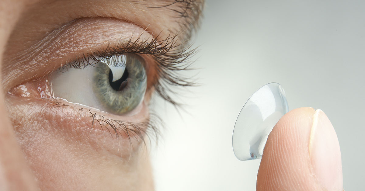 person putting contact lense in eye