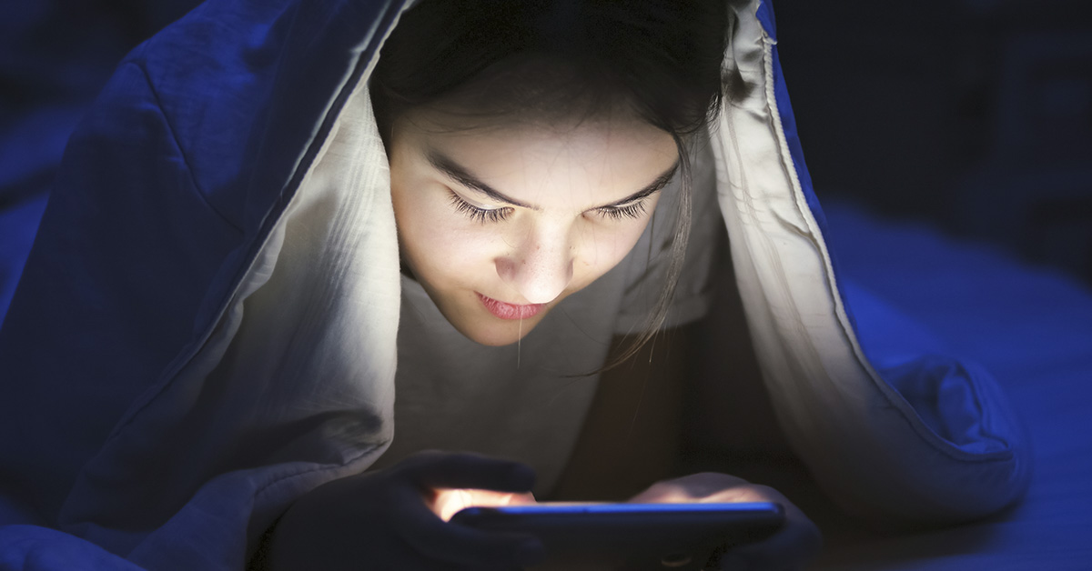 woman looking down at smartphone in low light area