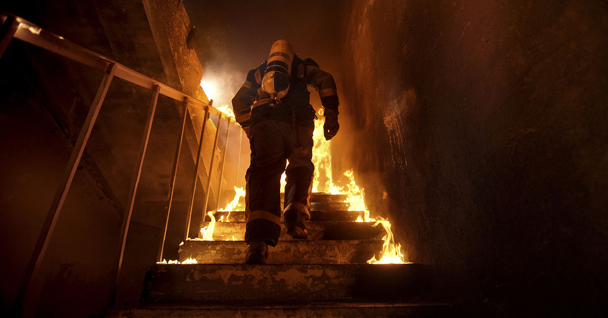firefighter running up the stairs in a burning house