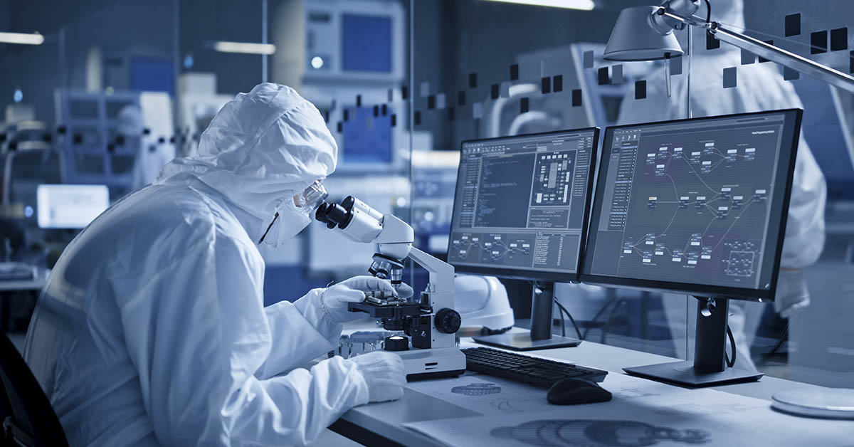 scientist in white lab suit using microscope