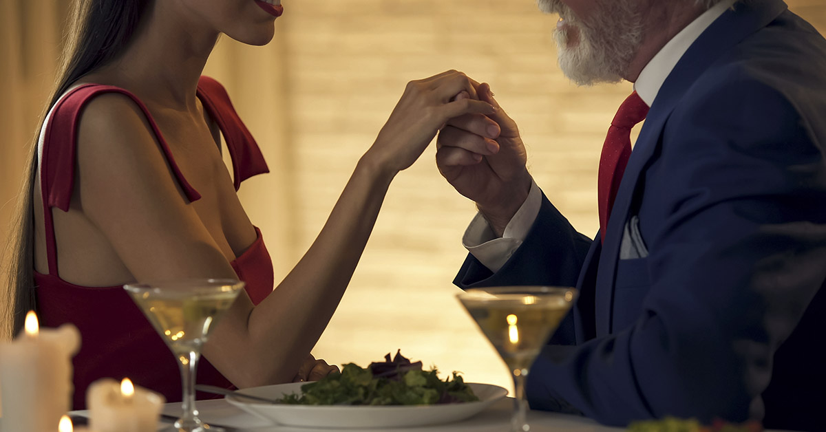 an older man holding a younger woman's hand in a romantic gesture