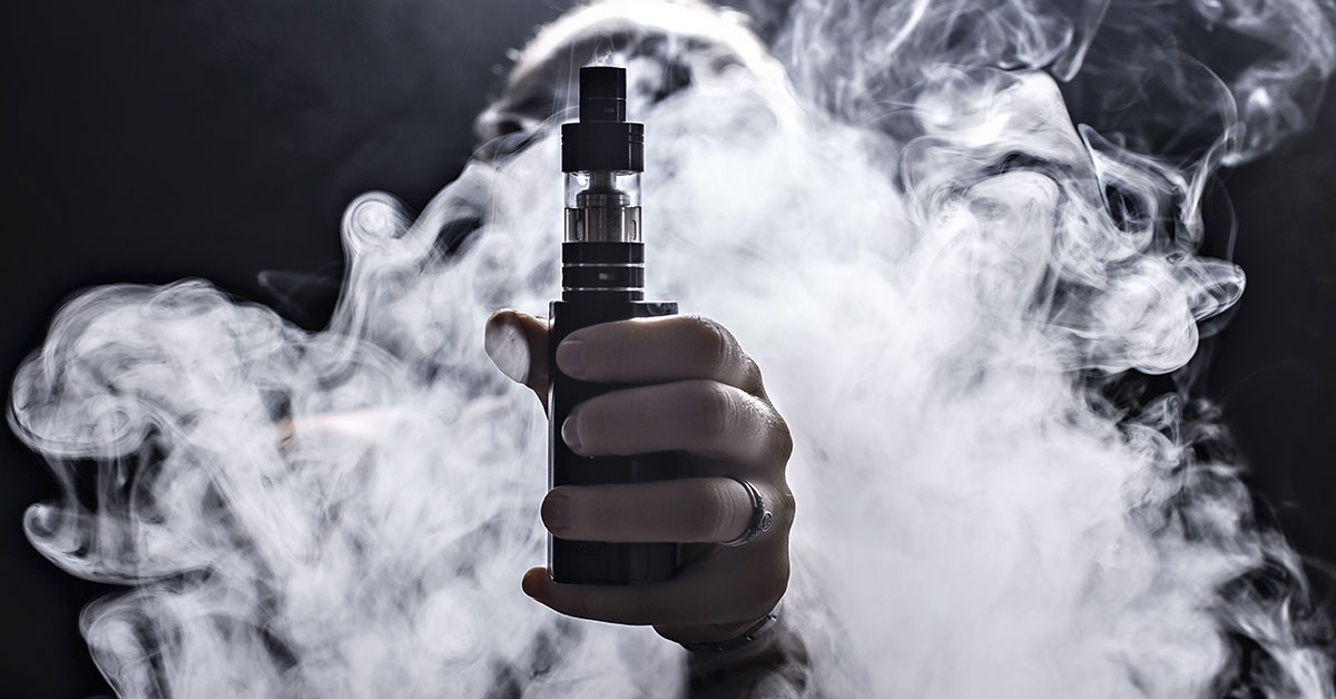 vape pen being held with vapour being emitted