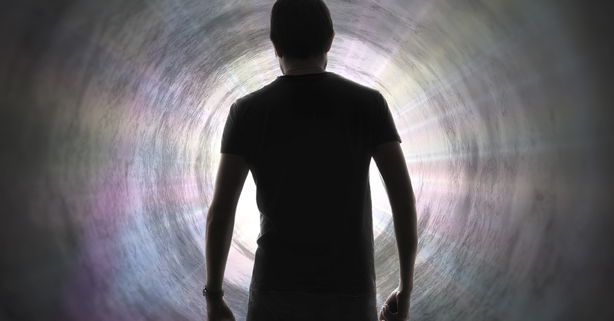 man walking into glowing white tunnel to represent the afterlife
