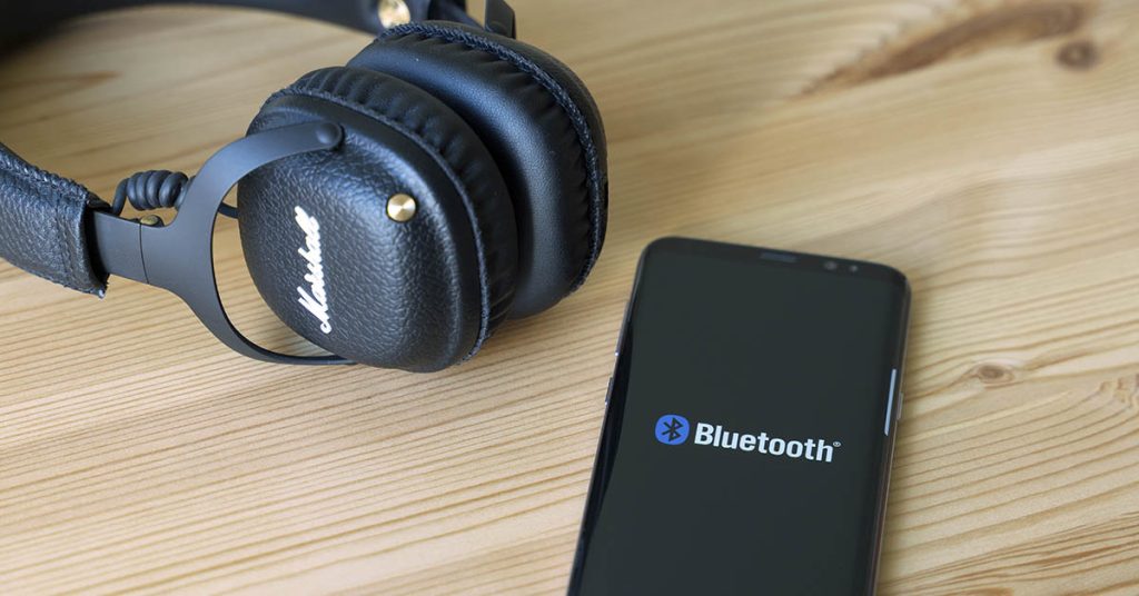 Smartphone with Bluetooth logo displayed and a pair of wireless Marshall branded earphones 