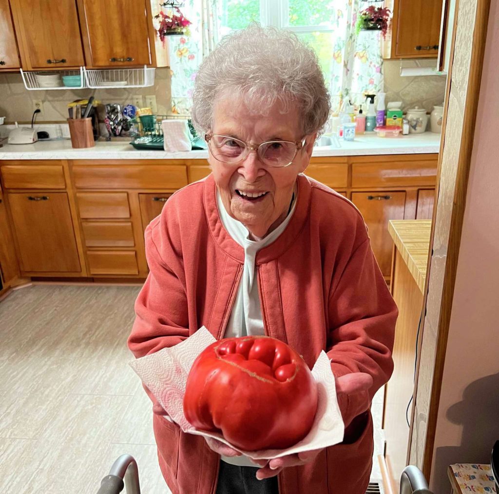 Sybil Gorby holding an heirloom tomato from her garden 