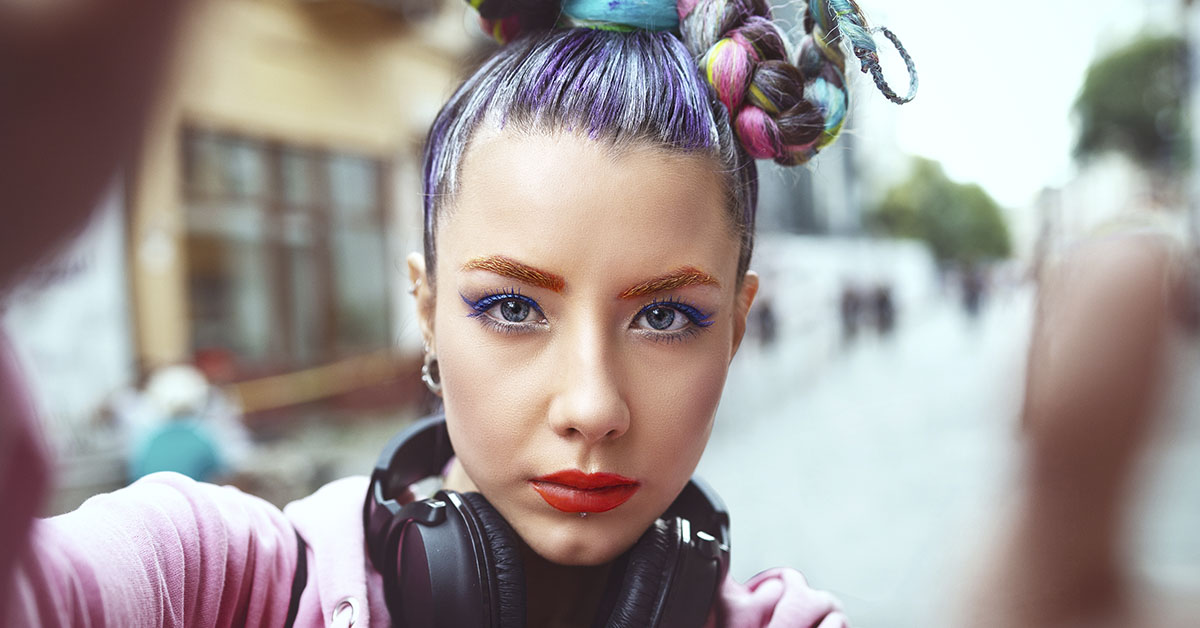 Gen Z woman with colored hair and earphones around neck
