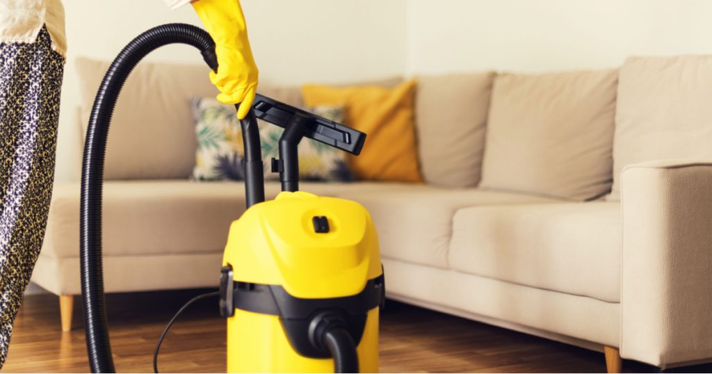 woman wearing yellow gloves with a yellow vacuum cleaner