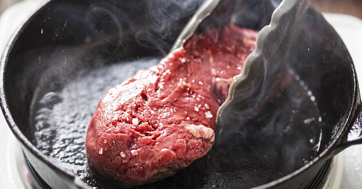 steak being grilled on cast iron skillet