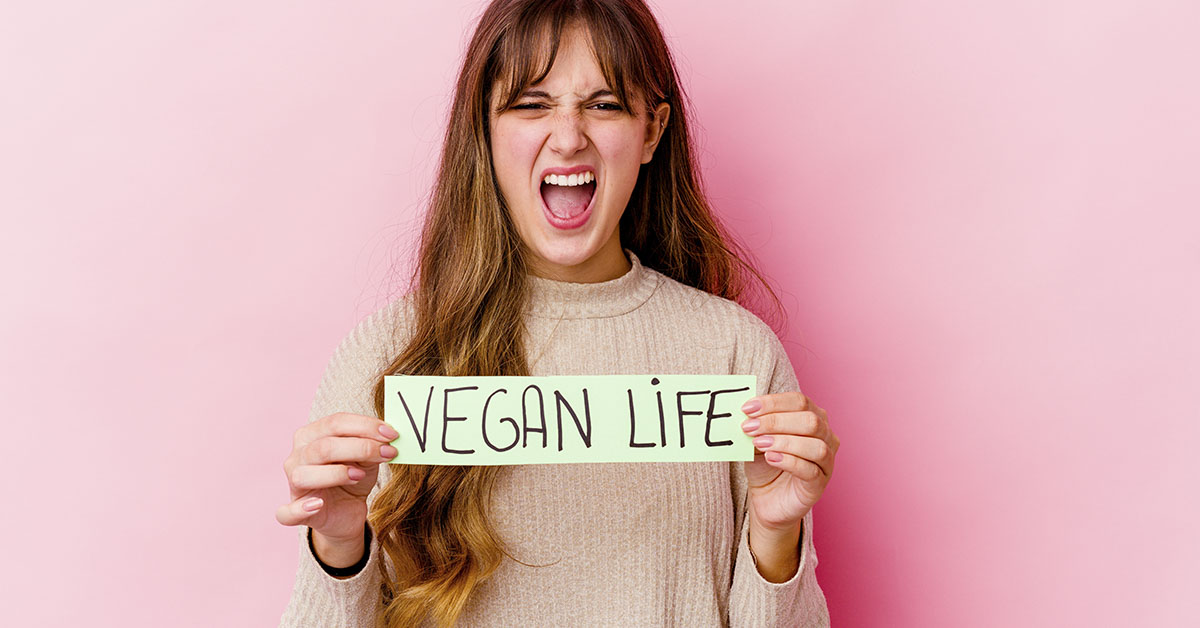pink background with woman yelling holding sign "Vegan life"