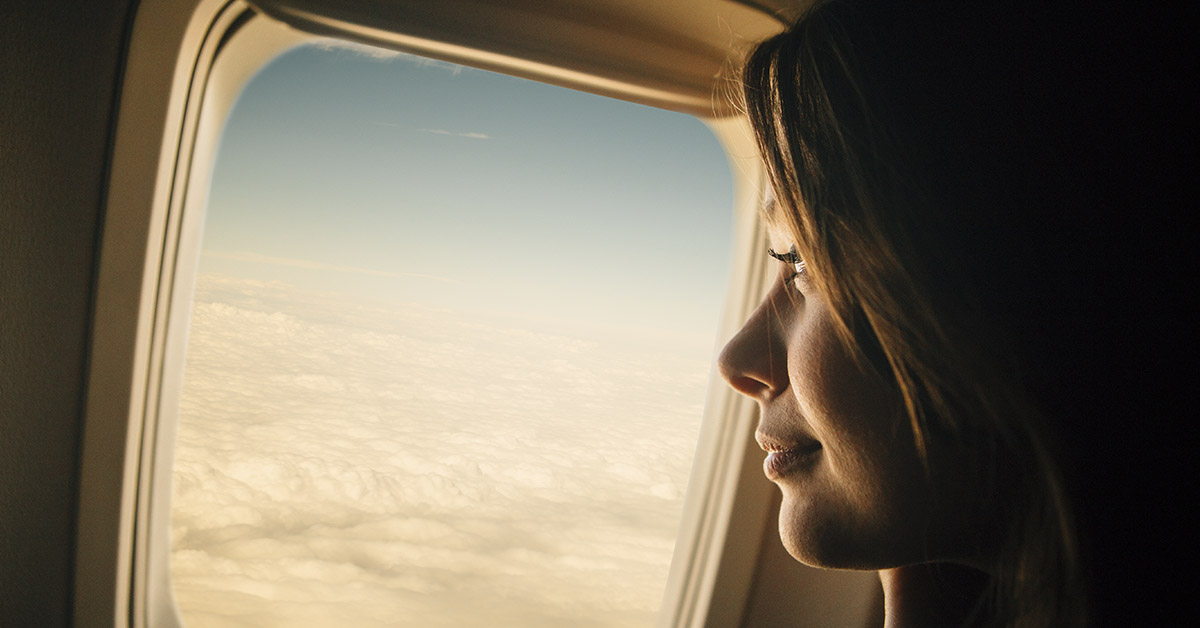 woman looking out the window of a plane