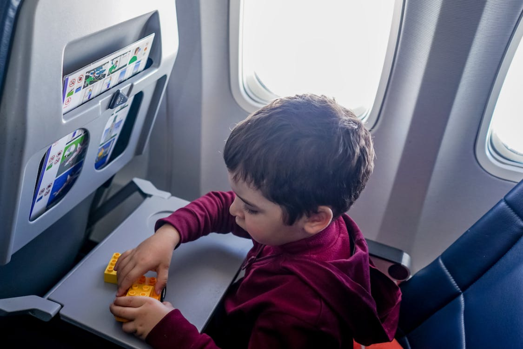 A boy playing with toys while sitting in the window seat on an airplane