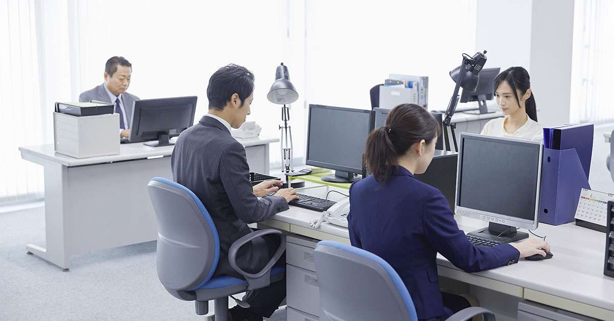 people in suits working at their computers in an office