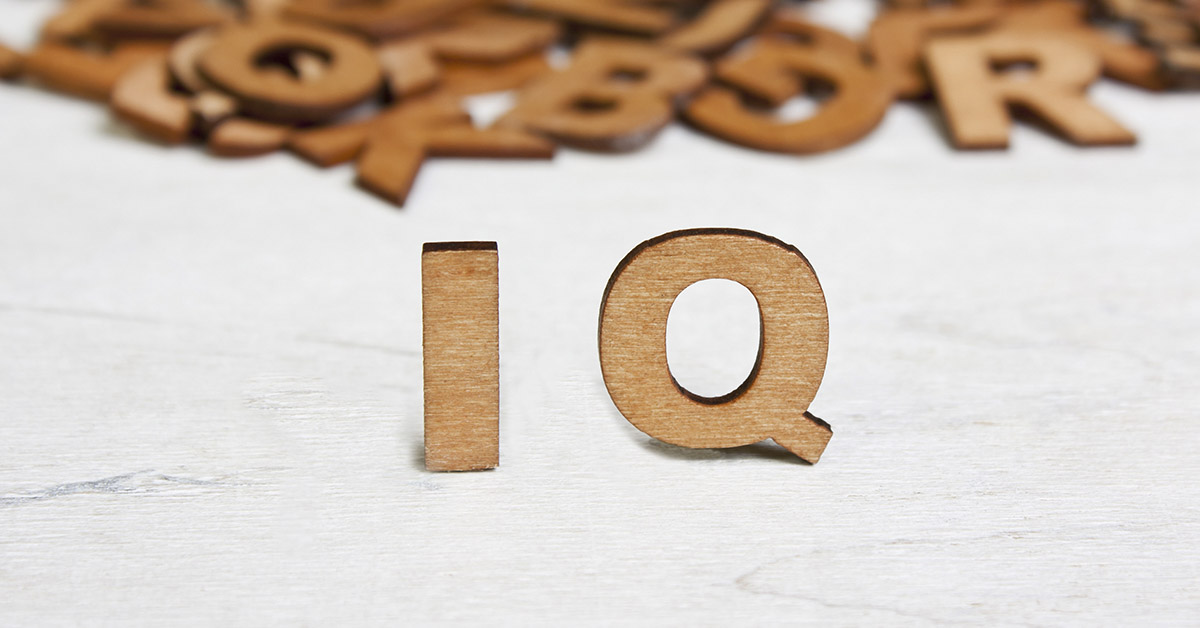 brown colored wooden letters in the background, and 'IQ' in the foreground. Intelligence and IQ concept