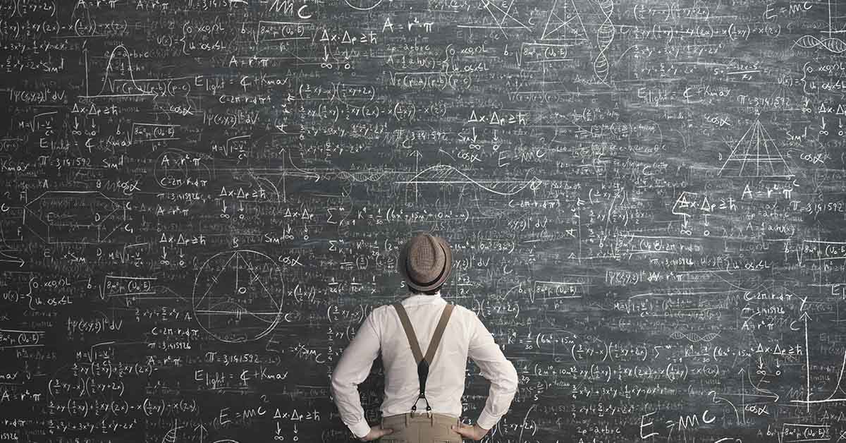 man standing in front of large chalkboard filled with various math equations