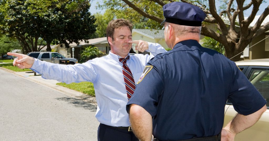 Police officer giving a roadside sobriety test to a drunk driver.