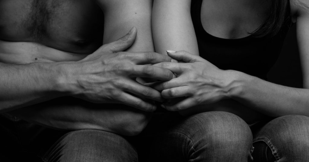 black and white photo of male and female hands touching each other's fingers. Hands of man and woman close-up.