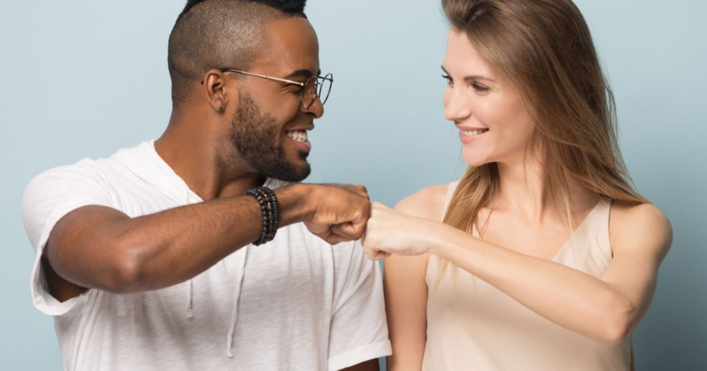 Excited african American man and Caucasian woman give fist bump