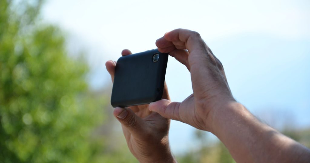 People hands held up in the air while recording with a mobile phone