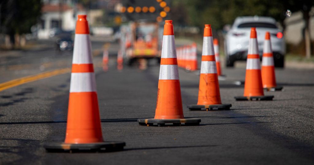 Traffic cones on road with electronic arrow pointing to the right to divert traffic and white car in distance