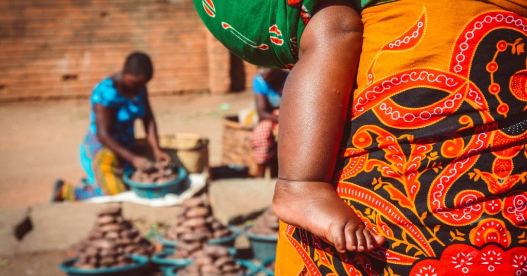 African woman is carrying her baby on the market
