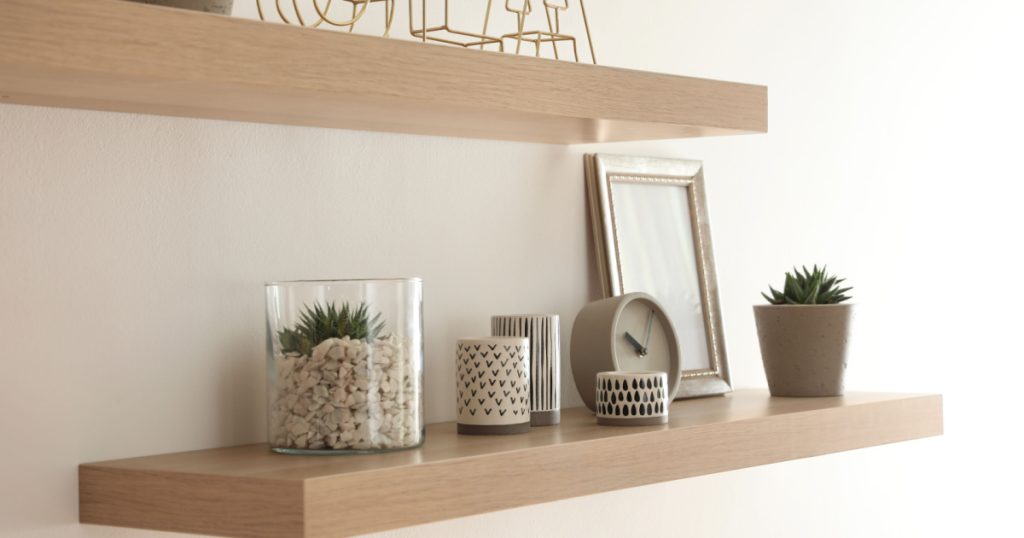 Wooden shelves with plants and decorative elements on light wall
