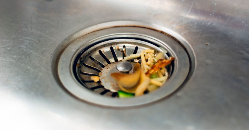 the leftovers of food left inside the kitchen sink are about to clog the drain. Food waste. Food leftovers that are compostable and reusable