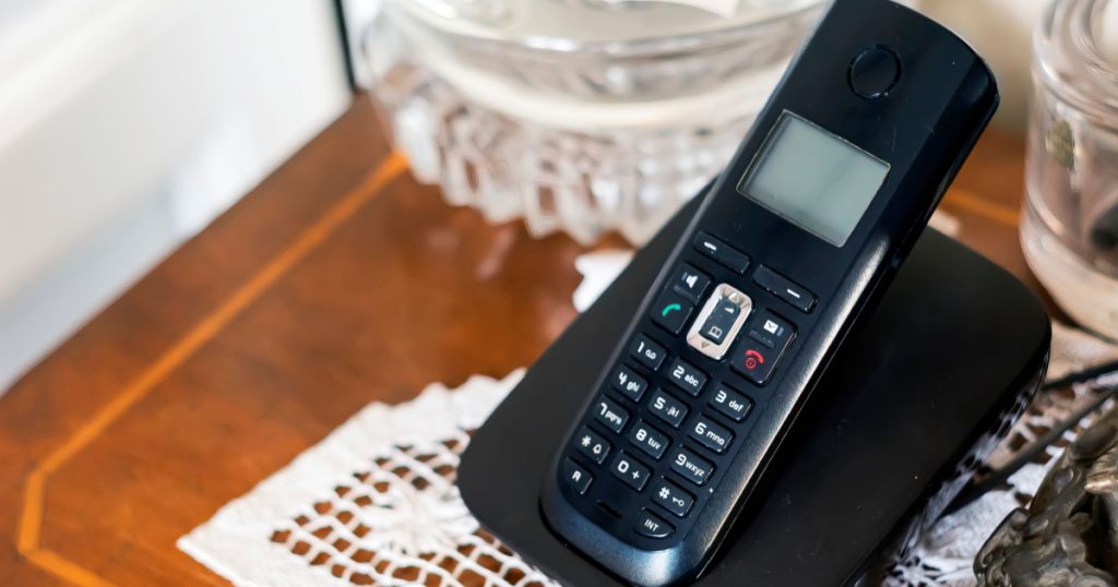black plastic cordless phone charging on its cradle 